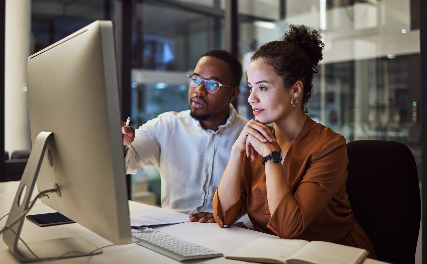 Two colleagues at a shared screen during a governance rollout.